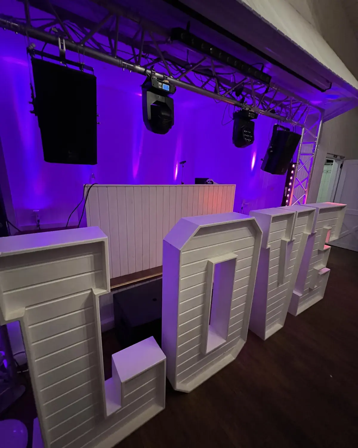 Beleuchtete LOVE-Buchstaben neben dem DJ-Pult einer Hochzeit