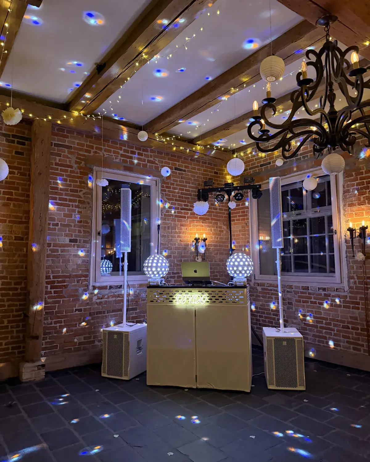 DJ-Pult in Location mit Backsteinwand und Lichterketten
