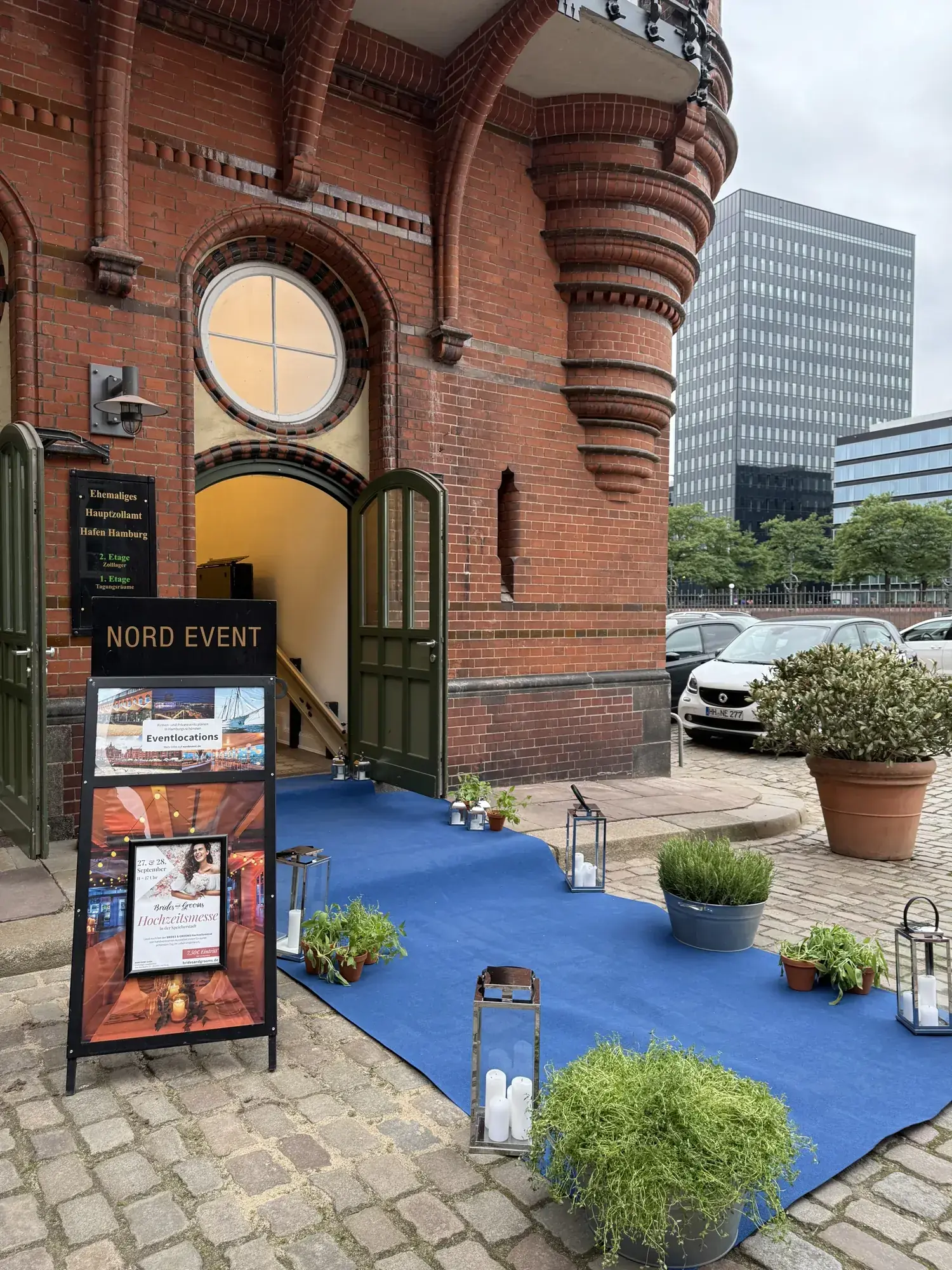 Eingang des Ehemaligen Hauptzollamts mit NORD-EVENT-Aufsteller, blauem Teppich und Laternen zur BRIDES & GROOMS