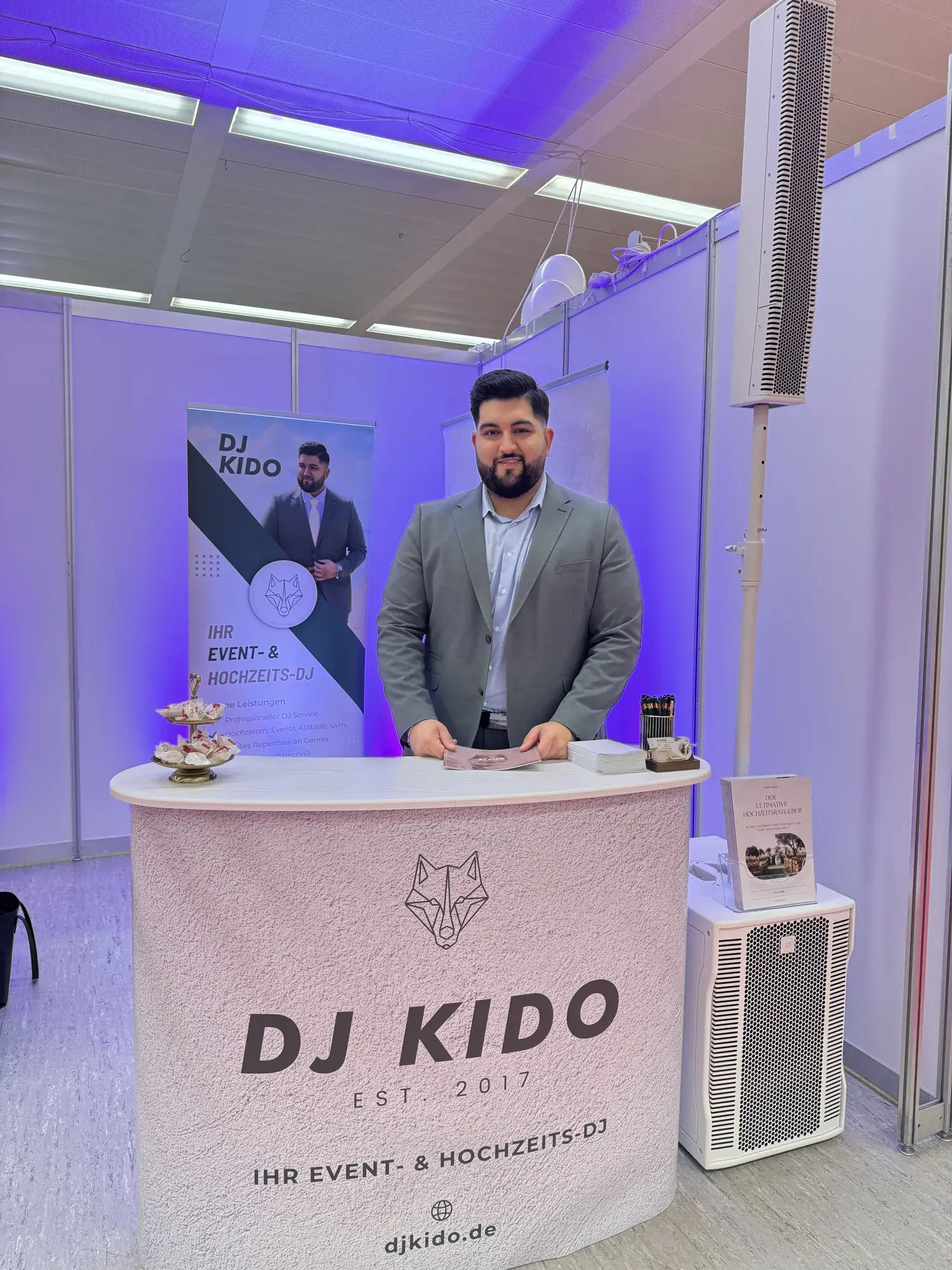 Ali Biabani, DJ Kido, hinter der Theke seines Messestands auf der TrauDich! Hamburg in der MesseHalle Schnelsen