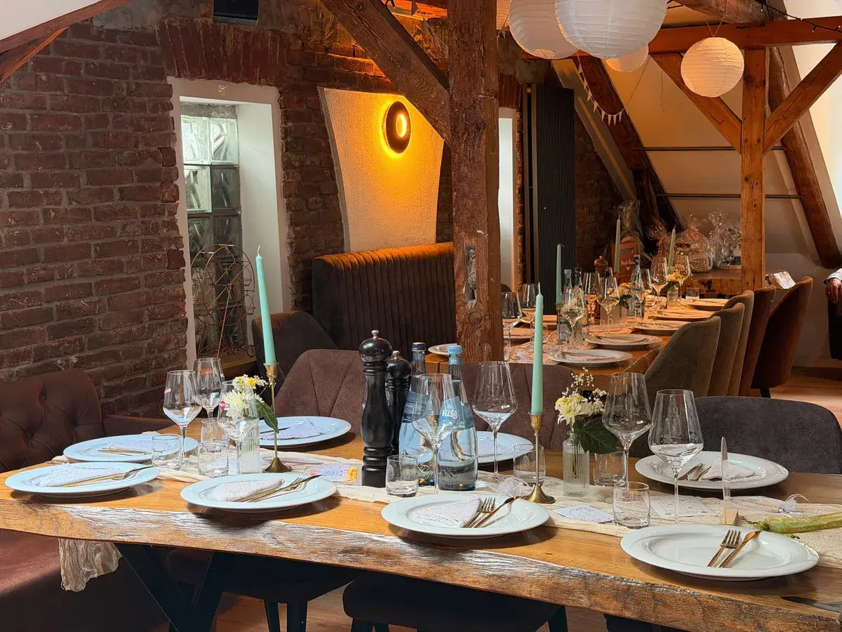 Lange Holztafel im Loft der Eppendorfer Insel mit Backsteinwand, Holzbalken und Lampions