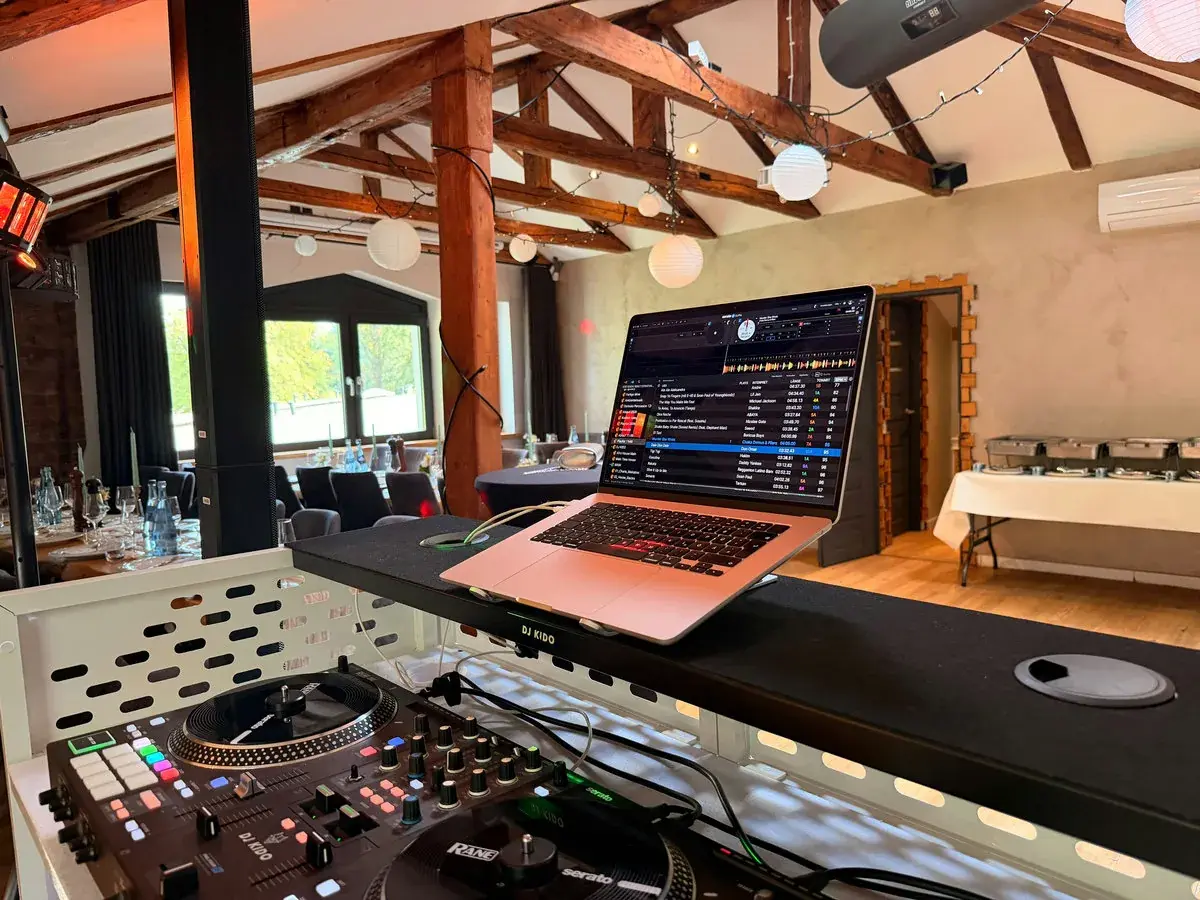 Blick vom DJ-Pult von DJ Kido über das Loft der Eppendorfer Insel mit Holzbalken, Lampions und gedeckten Tafeln