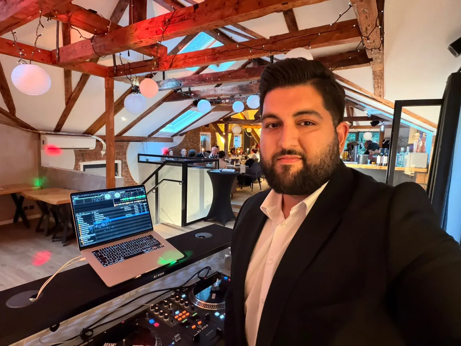 DJ Kido am Pult im Loft der Eppendorfer Insel, im Hintergrund die Gäste an den Tafeln unter dem Dachstuhl