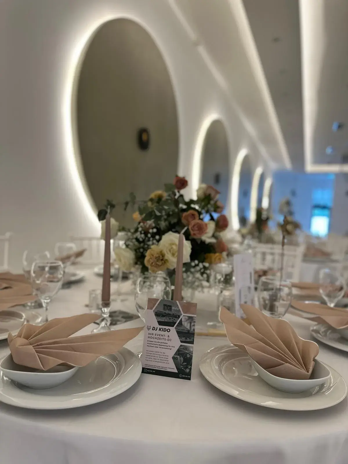 Hinterleuchtete Rundnischen an der Saalwand des Moon Events mit gedeckter Hochzeitstafel