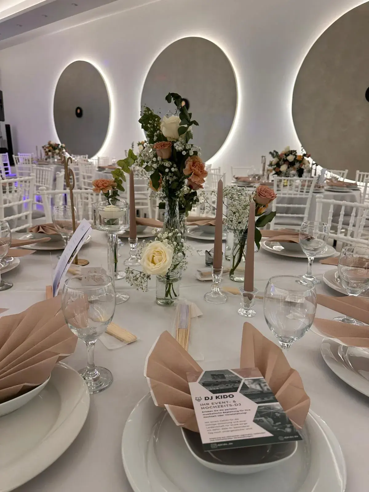 Hochzeitstafel im Moon Events mit Blumen, Kerzen und den beleuchteten Wandnischen im Hintergrund