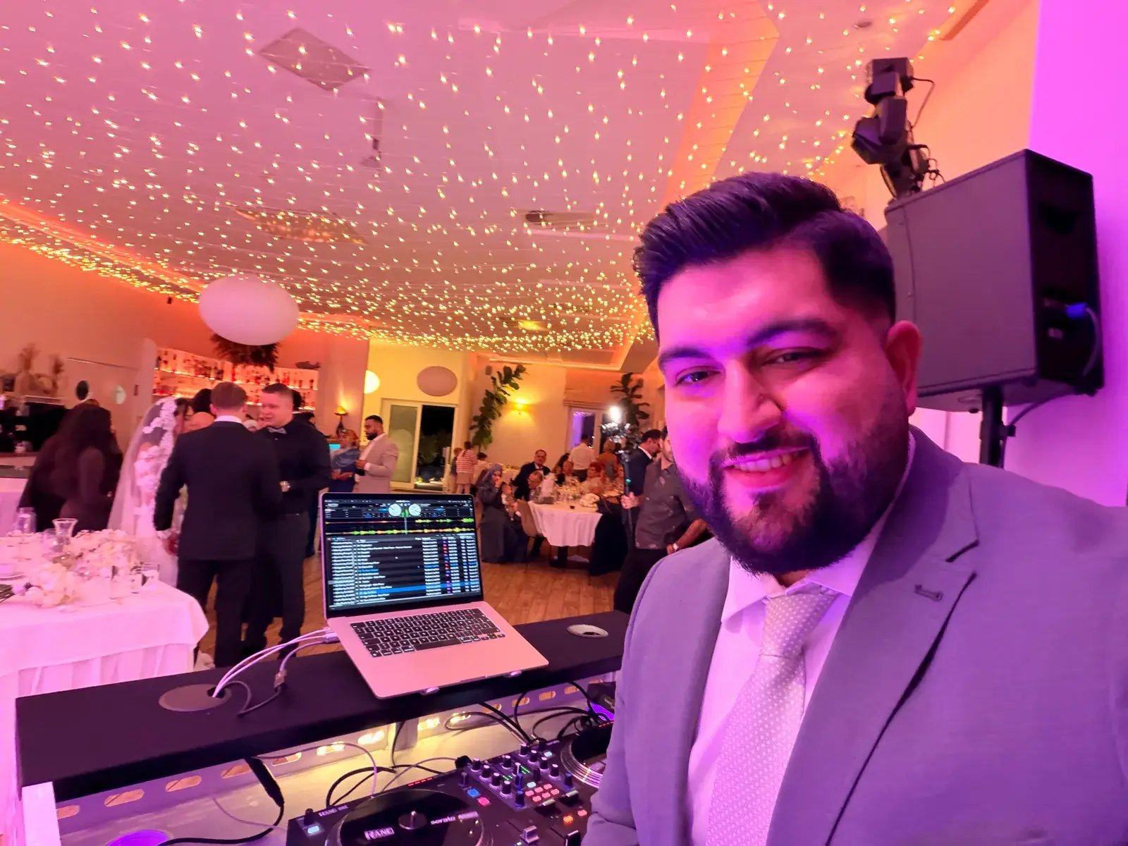 DJ Kido am Pult im Yachtblick Hamburg vor der Hochzeitsgesellschaft und der Decke aus warmen Lichterketten