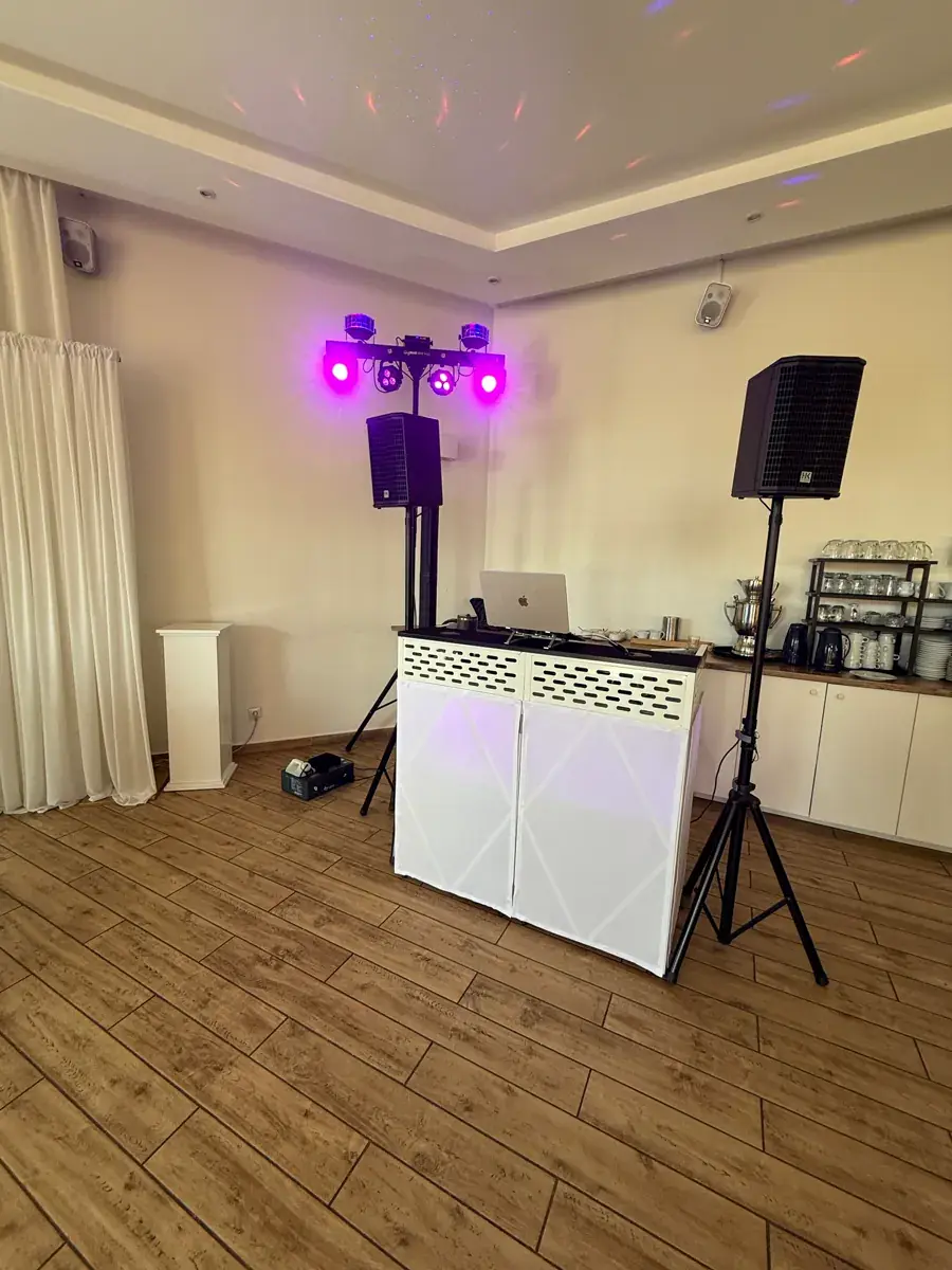 Weiße DJ-Booth von DJ Kido mit HK-Lautsprechern und violetter Lichtbar im hellen Saal des Yachtblick Hamburg
