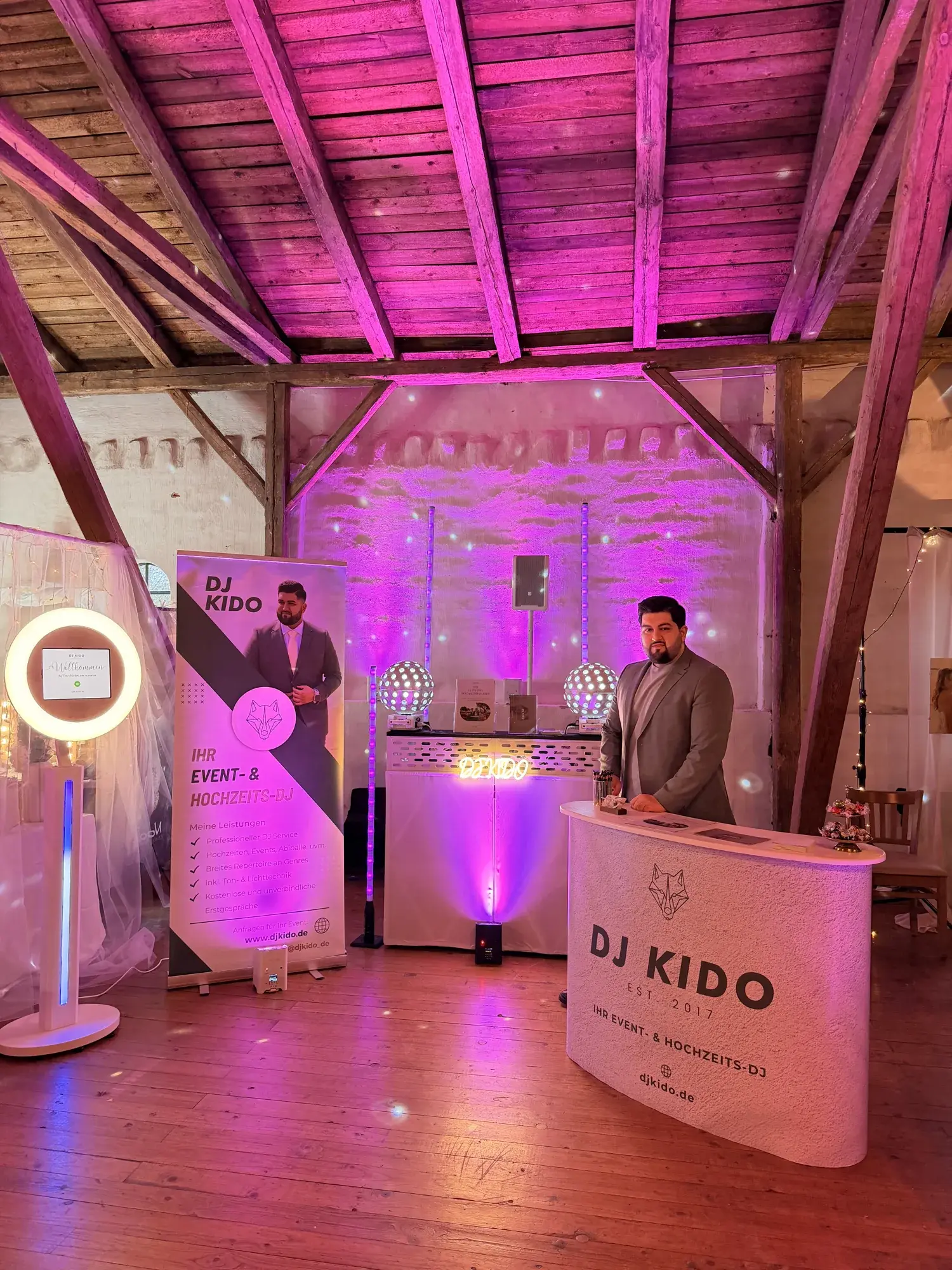 Ali Biabani, DJ Kido, an seinem Messestand in der Scheune von Gut Pronstorf, das Fachwerk in pinkem Licht