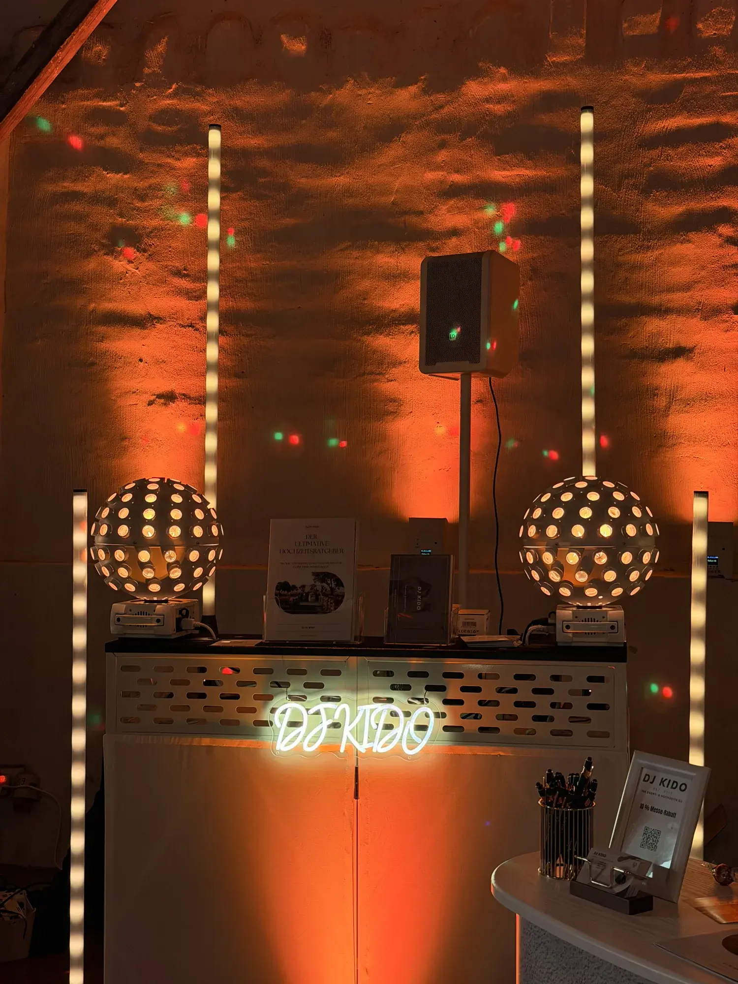 DJ-Booth mit Kugel-Lichteffekten vor der warm beleuchteten Feldsteinwand auf Gut Pronstorf